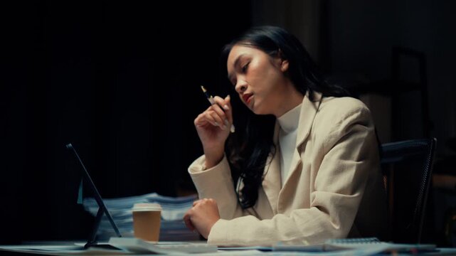 Businesswoman working late night at her office desk, deeply focused on a tablet screen, sipping coffee, and thinking critically