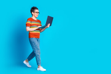 Full body portrait of nice aged lady walk use laptop empty space wear t-shirt isolated on blue color background