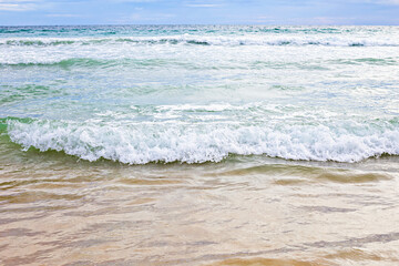 Gentle ocean waves rolling onto sandy shore, showcasing beauty of nature and tranquility of sea. Selective focus, defocus