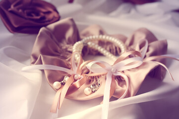 Lace garter on leg and bride's jewelry close-up, soft focus. Wedding attire details