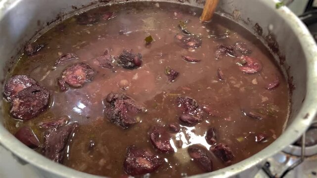 feijoada in a hot pan and a person stirring, typical Brazilian food