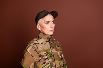 Photo of confident strong retired woman wear camouflage looking empty space isolated brown color background