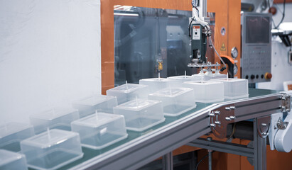 Plastic food containers on conveyor belt from plastic injection molding press machine. Industrial...