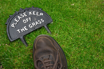 Please keep off the grass sign with foot on the grass