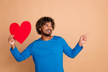 Photo of cheerful handsome man wear trendy blue clothes recommend empty space isolated on beige color background