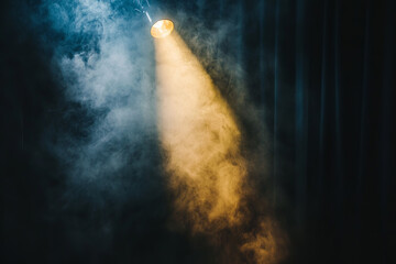 Obraz premium A vintage theatre spotlight beams through a black curtain, creating a dramatic shaft of light that pierces through swirling smoke