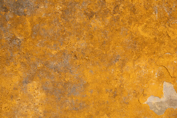 A close up of a weathered yellow wall The paint is peeling and the texture is rough