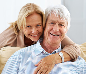 Senior, portrait and happy couple hug in house for love, support or laugh together in lounge. Face, man and woman embrace for connection, trust or commitment for marriage with partner in retirement