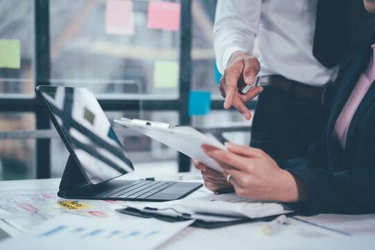 Guiding Collaboration: Business colleagues engage in focused teamwork, analyzing financial data on a tablet in a modern office setting.