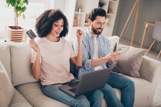 Photo of two people using netbook gadget sit couch buying online in room indoors - Powered by Adobe