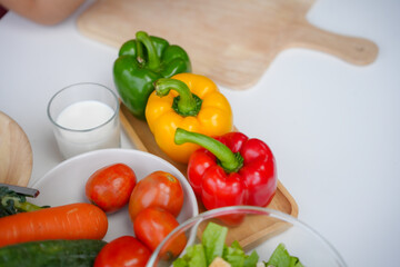 Nutritionist is preparing a healthy meal or snack with colorful fresh vegetables like bell peppers and tomatoes and a glass of milk