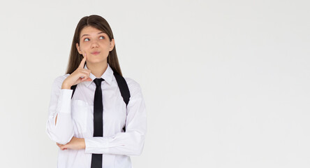 Cute woman thinking about smth. Young brunette student girl is thoughtful with backpack on white background