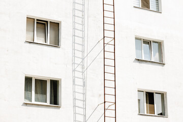 rustic panel concrete building exterior facade white wall plaster background windows and external stairs fire escape security landmark object perspective foreshortening concept