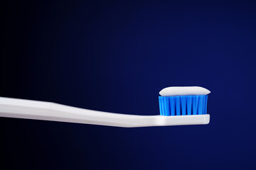 Dental king concept. Hygiene. Professional photo. White toothbrush with toothpaste on a dark blue background.