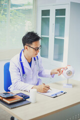 An ophthalmologist explains eye diseases using an eye model at an examination table in a hospital...