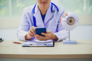 An ophthalmologist explains eye diseases using an eye model at an examination table in a hospital...