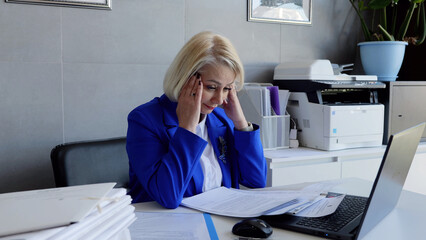 Businesswoman in office holding head in hands overworking emotional stress burnout. In office...