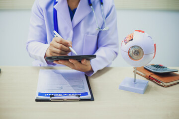 An ophthalmologist explains eye diseases using an eye model at an examination table in a hospital...