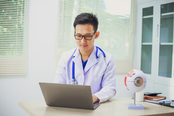 An ophthalmologist explains eye diseases using an eye model at an examination table in a hospital...