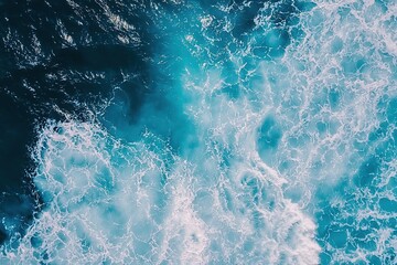 Fototapeta premium Aerial view of rough ocean waves creating dynamic pattern of blue water and white foam. Top shot of ocean texture perfect for backgrounds, nature themes and environmental content