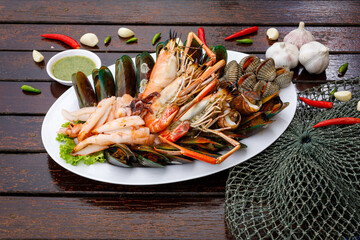 Seafood plate with shrimp shellfish crab squid cockle spotted babylon with seafood sauce chili lemon lime serve on dining table