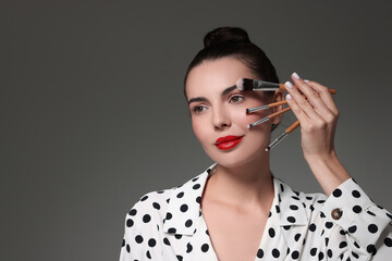 Obraz premium Beautiful makeup. Attractive woman with brushes on grey background, space for text