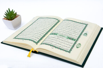 Obraz premium a hand pointing to the Muslim holy book al quran surat al khafi isolated on a white background with plants