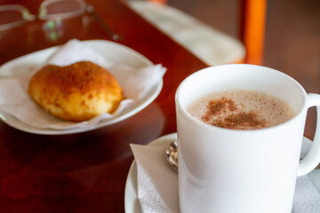 A hot cup of sweet mocha coffee and cocoa drink with a powdered cinnamon sprinkled on top of the froth foam of milk