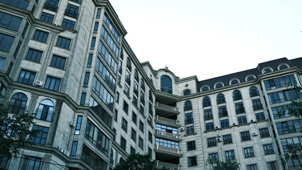 Majestic Multi-story Building with Neoclassical and Modern Elements, Featuring Arched Windows, Balconies, and Ornate Facade Details in a City Setting