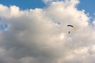 Parachuter with red canopy on cloudy sky