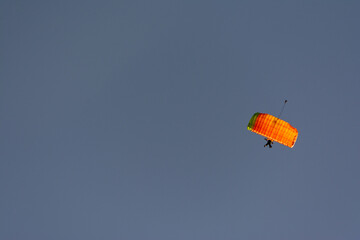 Orange canopy of parachuter on blue skies