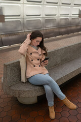 Young brunette looking down at cell phone at underground train station