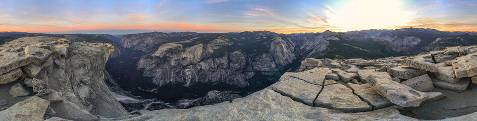 A panoramic view of a mountain range with a sunset in the background