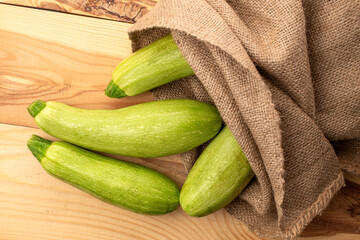 Several ripe zucchini with jute bag on wooden table, macro, top view.