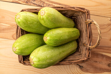 Several ripe zucchini with a basket on a wooden table, macro, top view.