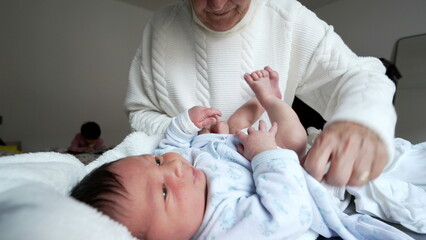Grandmother changing baby's diaper, nurturing and caring scene, infant lying down, family bonding...
