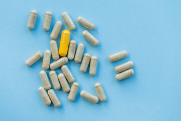 handful of medical capsules on bright plain blue background , alternative concept 