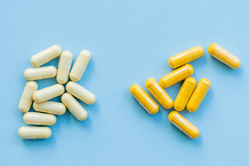 two heaps tablets of different colors yellow and white on a plain blue background, drug or medical...