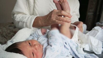 Grandmother changing newborn baby's diaper, gentle and nurturing care, intimate family moment,...
