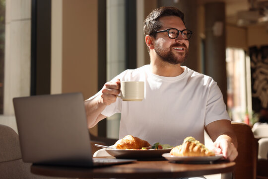 Happy man having tasty breakfast in cafe - Powered by Adobe