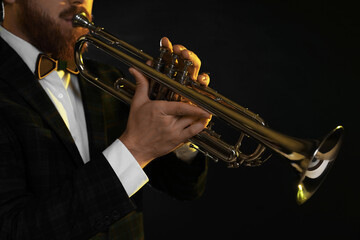 Obraz premium Professional musician playing trumpet on black background, closeup
