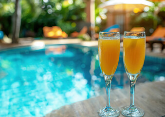Glasses of orange juice with orange slice near the swimming pool. Orange juice in champagne glass on edge the blue sky pool in party luxury hotel, thailand