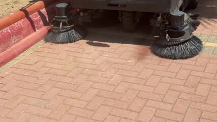 The vacuum cleaner machine cleans up trash on the sidewalk.