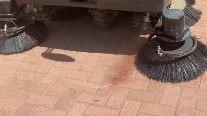 The vacuum cleaner machine cleans up trash on the sidewalk.