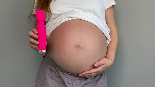 Happy pregnant young woman with sex toy for adults, female with vibrator 