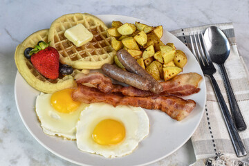 fried eggs with sausage , bacon and waffles