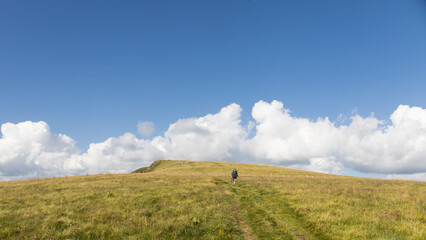 Obraz premium randonneur sur le GR400, le tour des monts du Cantal en été, avec vue sur les volcans cantaliens autour du Puy Gros