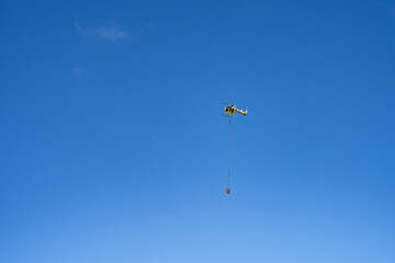 Fire helicopters fetch water from the sea to put out wildfires on the mountain. Mālaekahana State Recreation Area, Laie Bay, Oahu, Hawaii. Hukilau Beach Park

