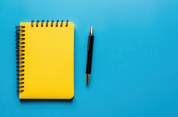 Yellow notebook with pen on blue background