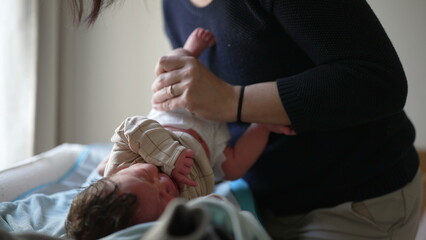 Obraz premium Mother dressing newborn baby, gently guiding arm into sleeve, emphasizing care and attention, capturing tender moments of bonding, showing love, early stages of infant care